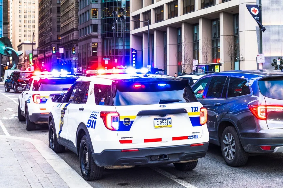 Police vehicles with flashing lights parked on a city street.