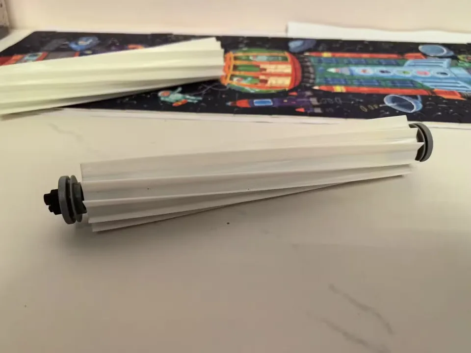 White replacement roller brush for a robot vacuum lying on a tabletop.