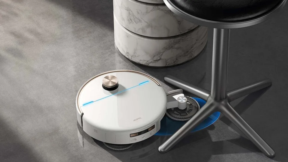White MOVA V70 Ultra robot vacuum cleaning beside a table base indoors.