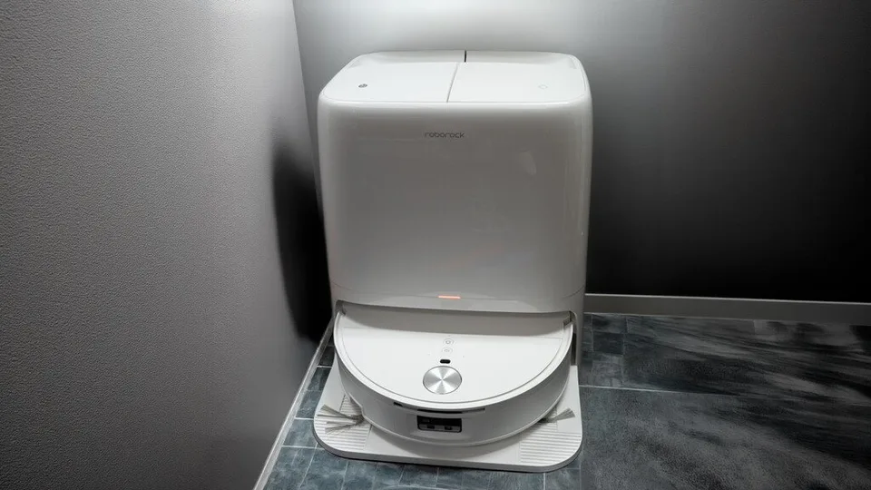 White Roborock Qrevo robot vacuum docked on its base beside a wall.