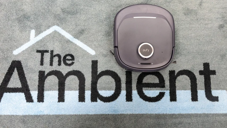 Eufy robot vacuum beside its docking station on a carpeted floor.