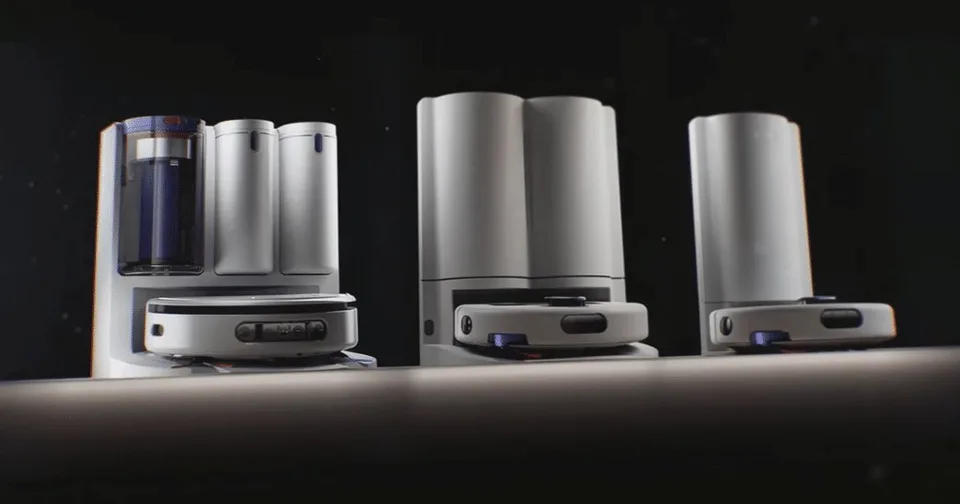 Three Dyson Nurovi robot cleaners and their tall docking stations arranged against a dark background.