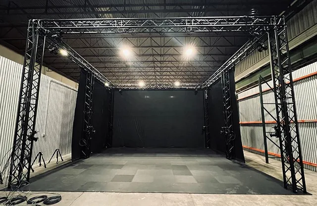 A motion-capture studio with a large open floor enclosed by camera rigs and black curtains.