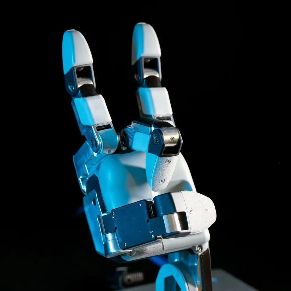 Close-up photograph of a blue-and-white robotic hand with two raised fingers against a black background.