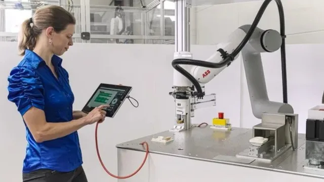 Worker uses a tablet beside an ABB robotic arm in an industrial workcell.