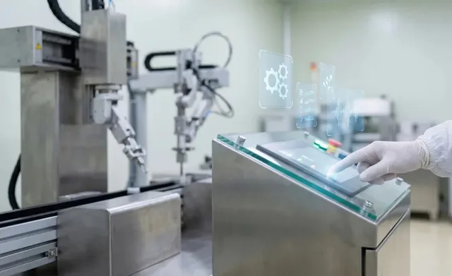 Industrial robotic arms operating beside a touchscreen control panel in a factory setting.